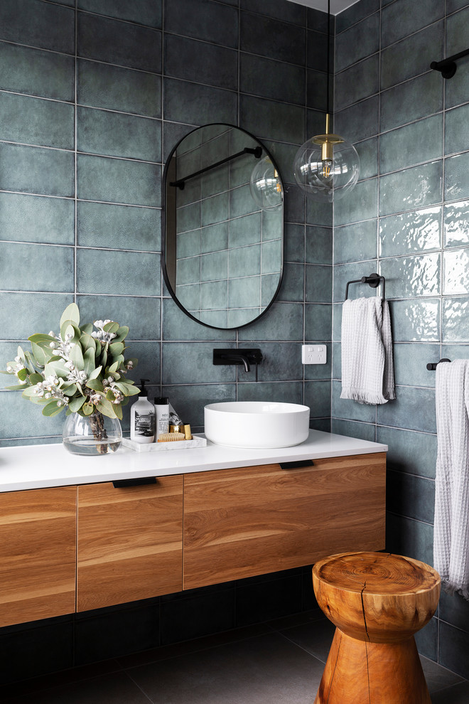 Photo of a mid-sized modern 3/4 bathroom in Canberra - Queanbeyan with medium wood cabinets, a freestanding tub, an open shower, a one-piece toilet, green tile, green walls, porcelain floors, a vessel sink, engineered quartz benchtops, grey floor, an open shower and white benchtops.
