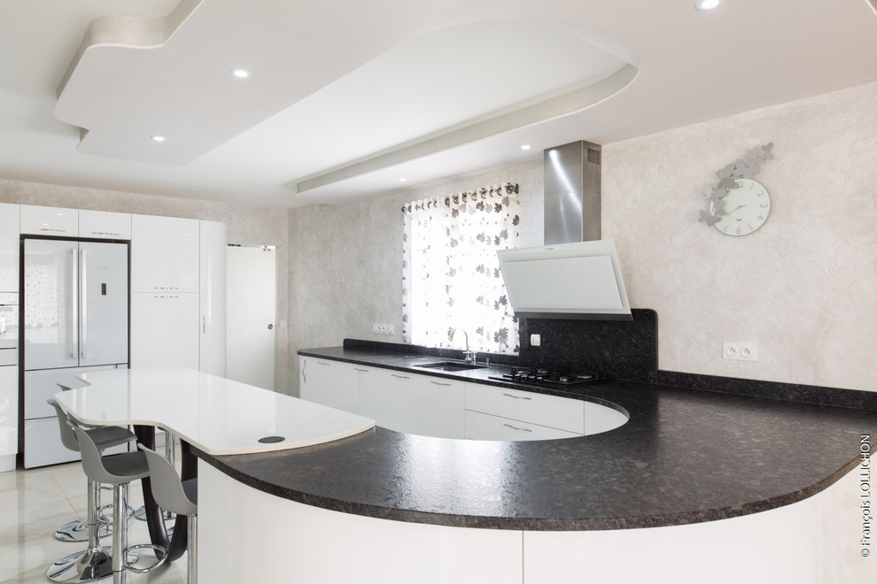 Mid-sized contemporary u-shaped open plan kitchen in Paris with an integrated sink, recessed-panel cabinets, white cabinets, granite benchtops, grey splashback, white appliances, no island and beige floor.