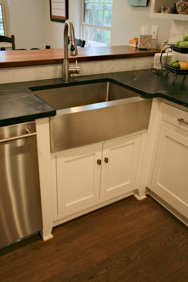 Example of a mid-sized l-shaped dark wood floor kitchen design in Cincinnati with a farmhouse sink, flat-panel cabinets, white cabinets, soapstone countertops, white backsplash, stone tile backsplash, stainless steel appliances and a peninsula