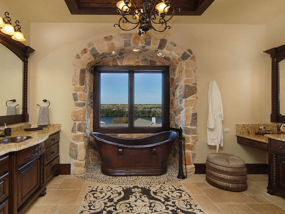 This is an example of a large mediterranean master bathroom in Dallas with dark wood cabinets, a freestanding tub, beige walls, ceramic floors, granite benchtops, a drop-in sink and raised-panel cabinets.