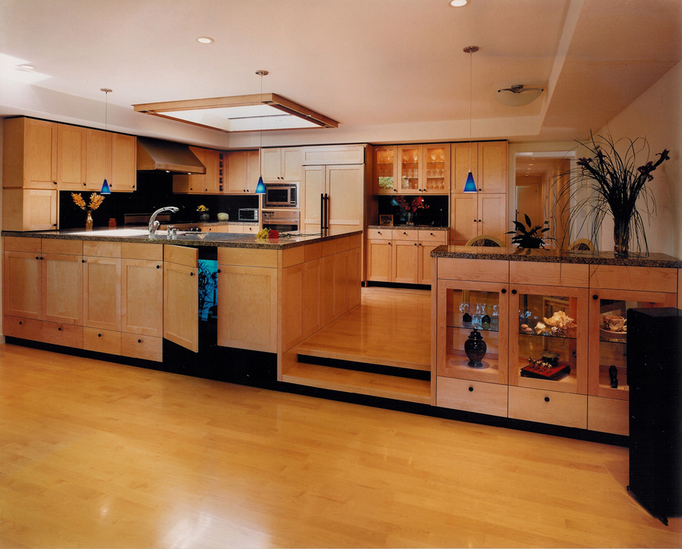 Large contemporary u-shaped eat-in kitchen in San Francisco with a double-bowl sink, shaker cabinets, light wood cabinets, granite benchtops, black splashback, stainless steel appliances, light hardwood floors, stone slab splashback, a peninsula, yellow floor and brown benchtop.