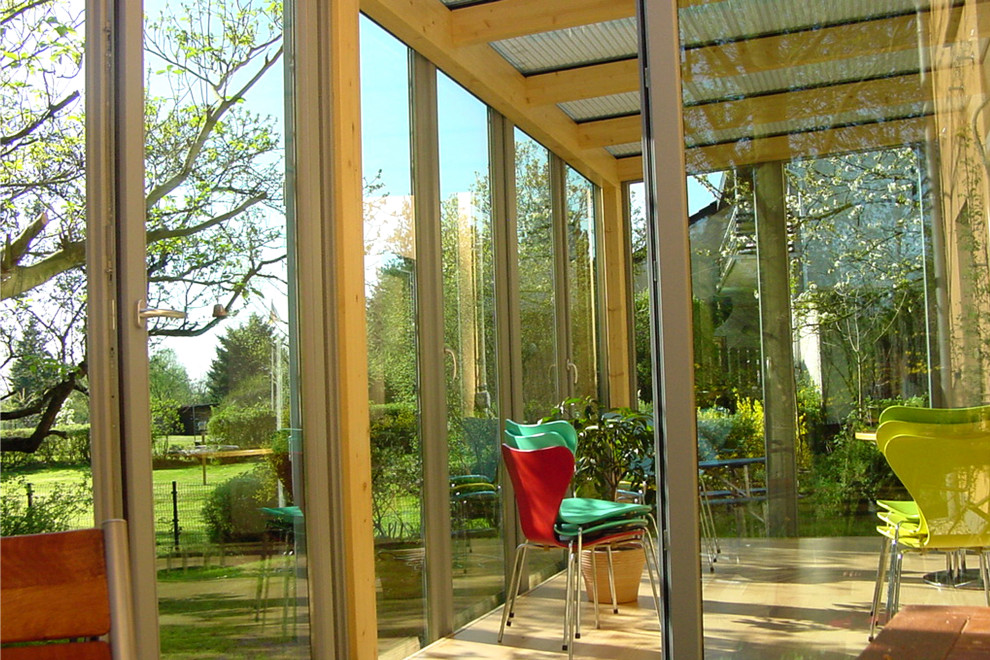 Mittelgroßer Moderner Wintergarten mit hellem Holzboden, Glasdecke und braunem Boden