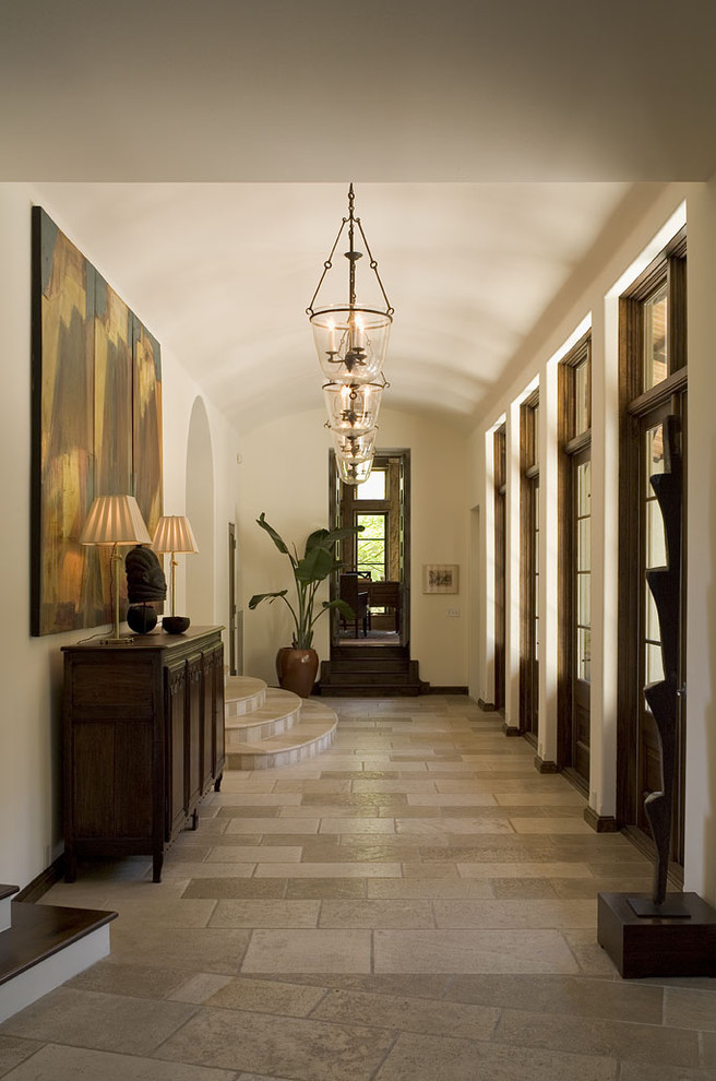 Traditional hallway in Austin with white walls and travertine floors.