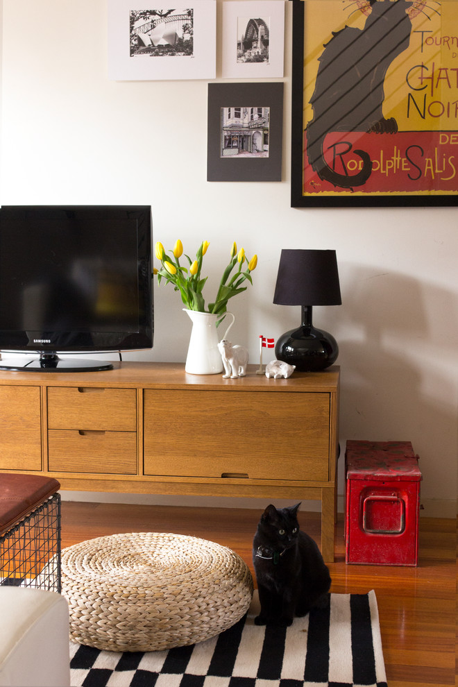 Mittelgroßes, Offenes Stilmix Wohnzimmer mit weißer Wandfarbe, braunem Holzboden und freistehendem TV in Melbourne