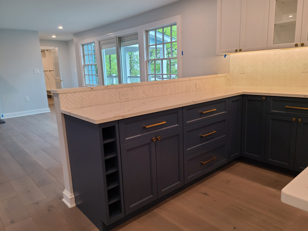 Design ideas for a large modern u-shaped eat-in kitchen in Boston with an undermount sink, shaker cabinets, blue cabinets, quartz benchtops, white splashback, marble splashback, stainless steel appliances, medium hardwood floors, with island, brown floor and white benchtop.