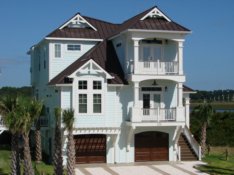 This is an example of a beach style three-storey blue house exterior in Other with wood siding and a hip roof.