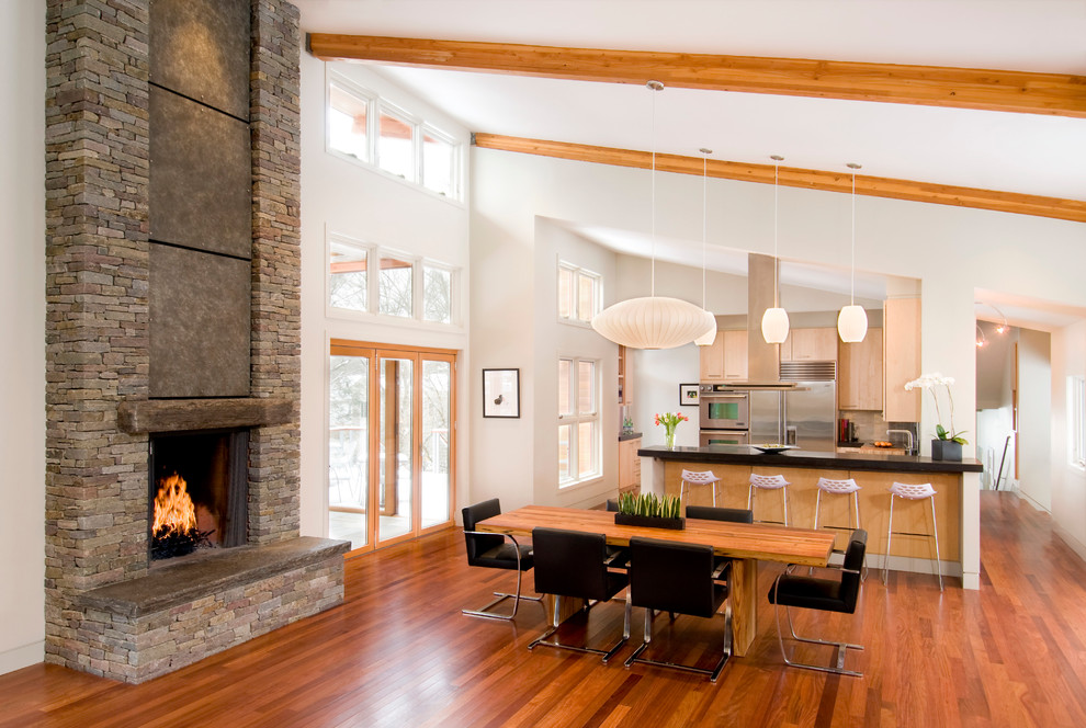 Inspiration for a contemporary kitchen/dining combo in Boston with white walls, dark hardwood floors, a standard fireplace and a stone fireplace surround.