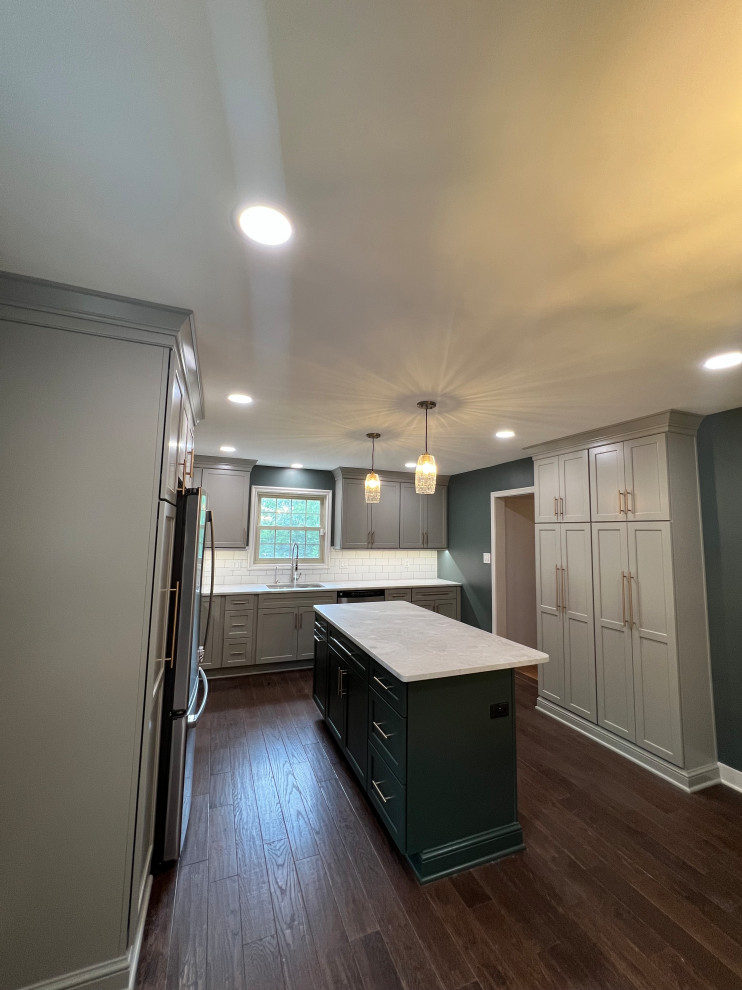Inspiration for a mid-sized transitional dark wood floor and brown floor kitchen remodel with an undermount sink, recessed-panel cabinets, gray cabinets, quartz countertops, white backsplash, subway tile backsplash, stainless steel appliances, an island and white countertops