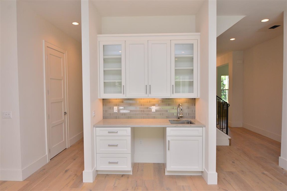 Example of a trendy light wood floor home bar design in Orlando with an undermount sink, shaker cabinets, white cabinets, quartzite countertops, gray backsplash and ceramic backsplash