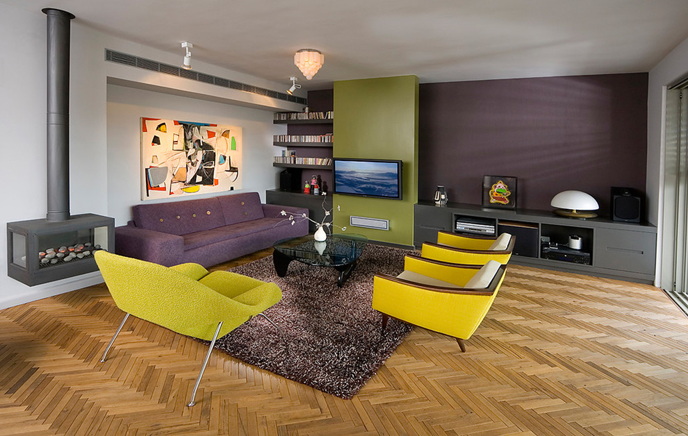 This is an example of a midcentury living room in Other with purple walls, medium hardwood floors and a hanging fireplace.
