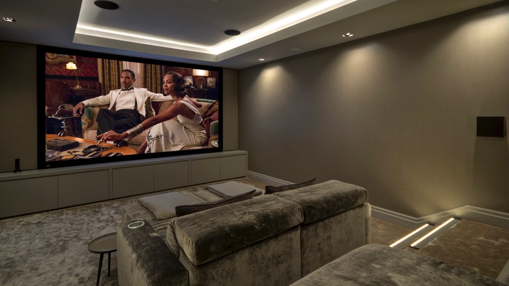 Photo of a large contemporary enclosed home theatre in Kent with brown walls, carpet, a projector screen and beige floor.
