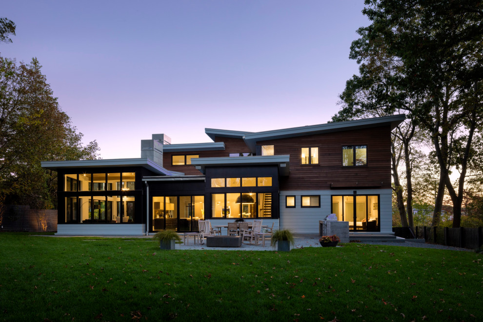 Пример оригинального дизайна: большой, двухэтажный, коричневый частный загородный дом в стиле модернизм с комбинированной облицовкой, крышей-бабочкой, металлической крышей и черной крышей