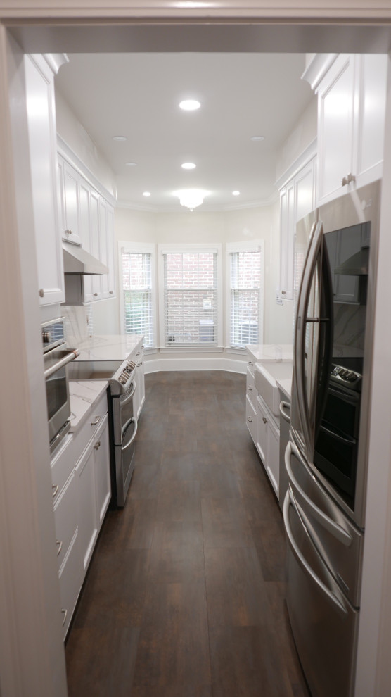Mid-sized transitional galley laminate floor and multicolored floor eat-in kitchen photo with a farmhouse sink, shaker cabinets, white cabinets, quartz countertops, white backsplash, quartz backsplash, stainless steel appliances and white countertops