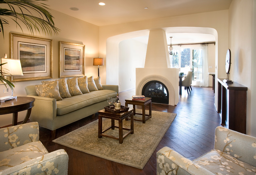 Mid-sized mediterranean formal open concept living room in Santa Barbara with beige walls, a two-sided fireplace, dark hardwood floors, a plaster fireplace surround and no tv.