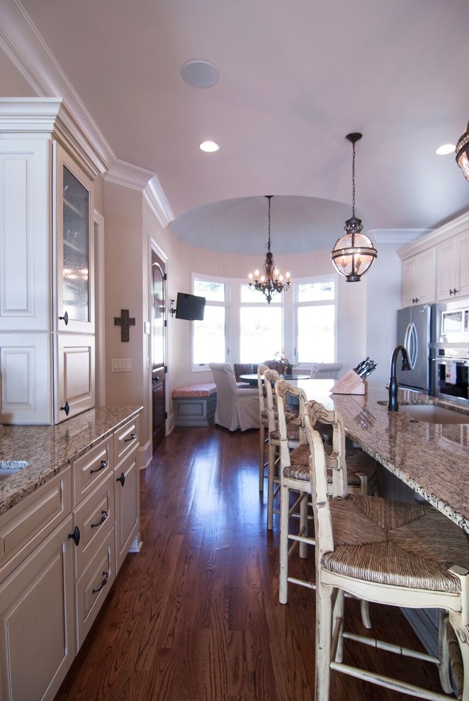 This is an example of a transitional kitchen in Charlotte with an undermount sink, raised-panel cabinets, white cabinets, granite benchtops, beige splashback, stainless steel appliances and medium hardwood floors.