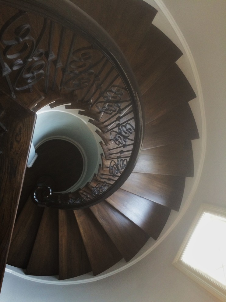 Large contemporary wood spiral staircase in Charlotte with wood risers.