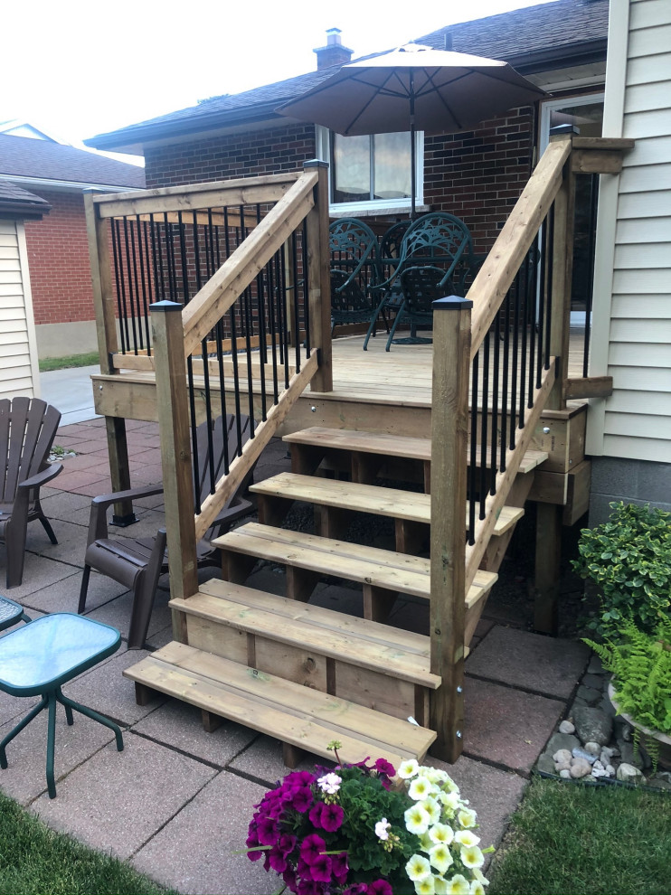 Example of a mid-sized backyard deck design in Toronto with no cover