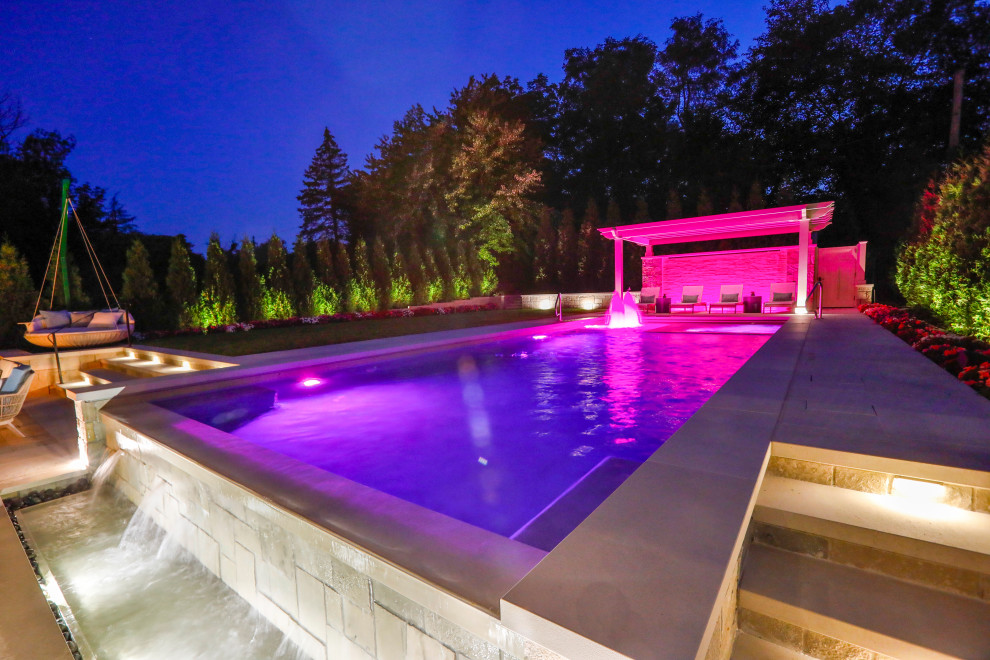 Esempio di una piscina monocorsia classica rettangolare di medie dimensioni e dietro casa con paesaggistica bordo piscina e pavimentazioni in pietra naturale