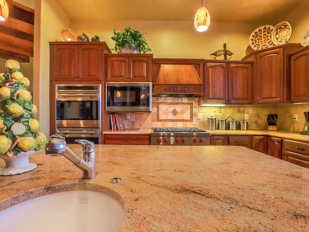 Large u-shaped eat-in kitchen in Albuquerque with an undermount sink, recessed-panel cabinets, medium wood cabinets, granite benchtops, beige splashback, ceramic splashback, stainless steel appliances, slate floors, with island, multi-coloured floor and brown benchtop.