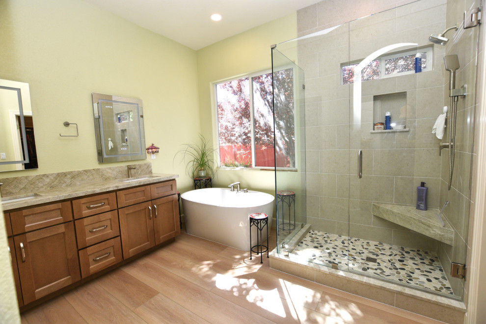 Large transitional master gray tile and porcelain tile vinyl floor, beige floor and double-sink corner shower photo with shaker cabinets, medium tone wood cabinets, a two-piece toilet, green walls, an undermount sink, quartzite countertops, a hinged shower door, beige countertops and a built-in vanity