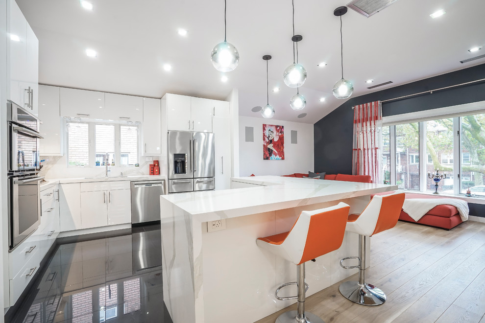 Large contemporary galley eat-in kitchen in New York with an undermount sink, flat-panel cabinets, white cabinets, quartz benchtops, multi-coloured splashback, stone slab splashback, stainless steel appliances, porcelain floors, multiple islands, black floor and white benchtop.