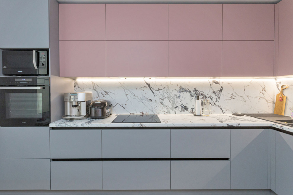 This is an example of a medium sized contemporary l-shaped kitchen/diner in Saint Petersburg with a single-bowl sink, flat-panel cabinets, grey cabinets, white splashback, black appliances and white worktops.