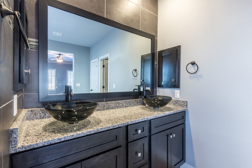Example of a large transitional master gray tile and ceramic tile ceramic tile home design design in Austin with flat-panel cabinets, brown cabinets, a one-piece toilet, gray walls, a vessel sink and granite countertops