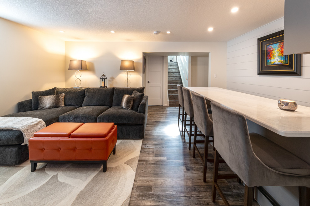 Design ideas for a mid-sized modern fully buried basement in Edmonton with a home bar, white walls, vinyl floors, a standard fireplace, a tile fireplace surround, brown floor and planked wall panelling.