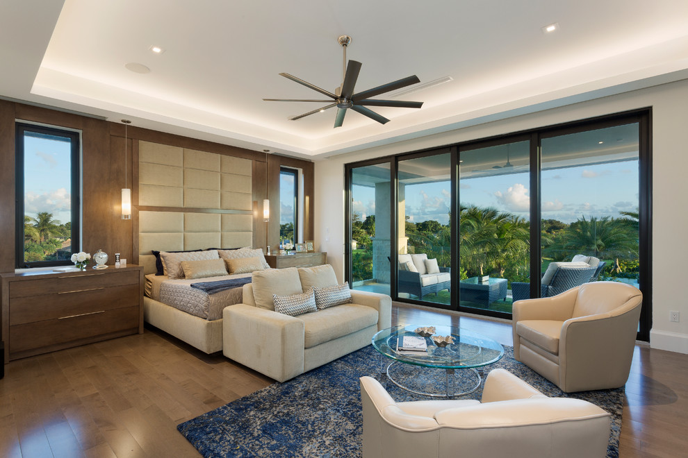This is an example of a large modern master bedroom in Miami with white walls, medium hardwood floors and brown floor.