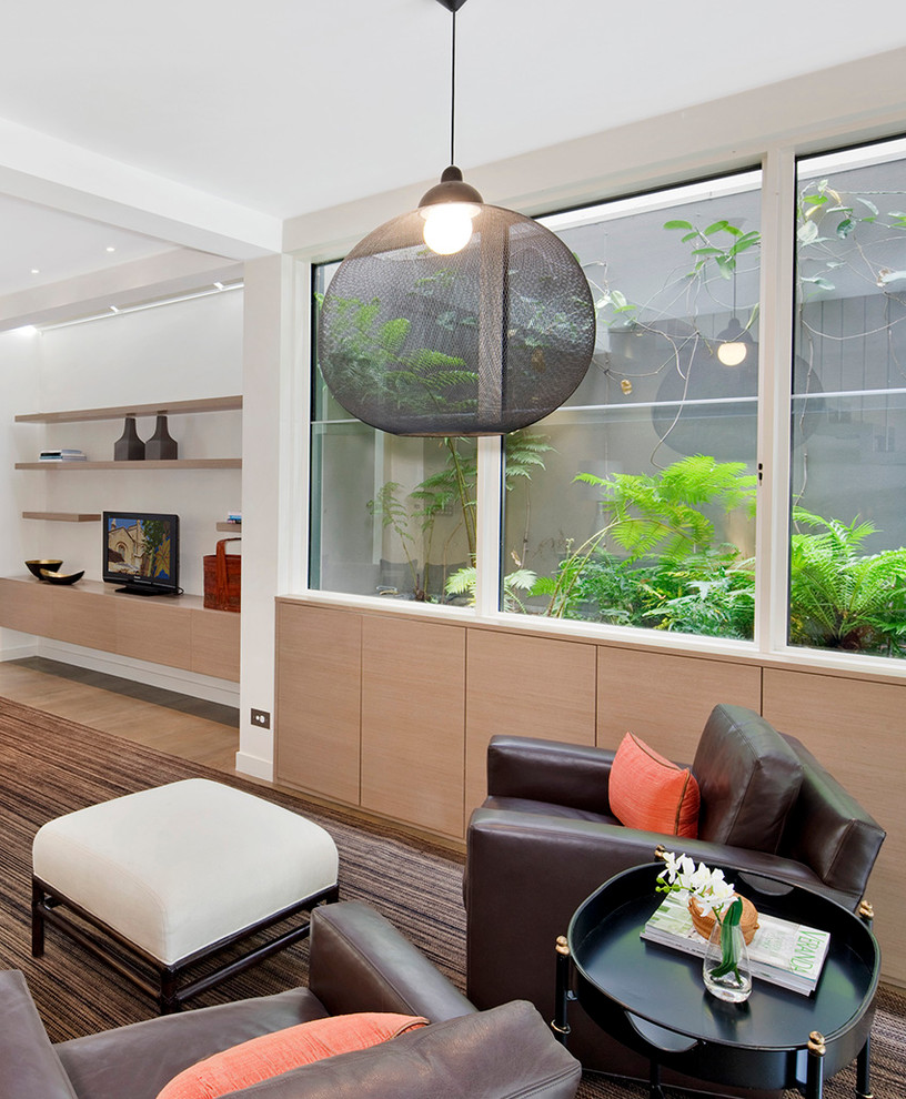 This is an example of a contemporary open concept family room in Sydney with white walls.
