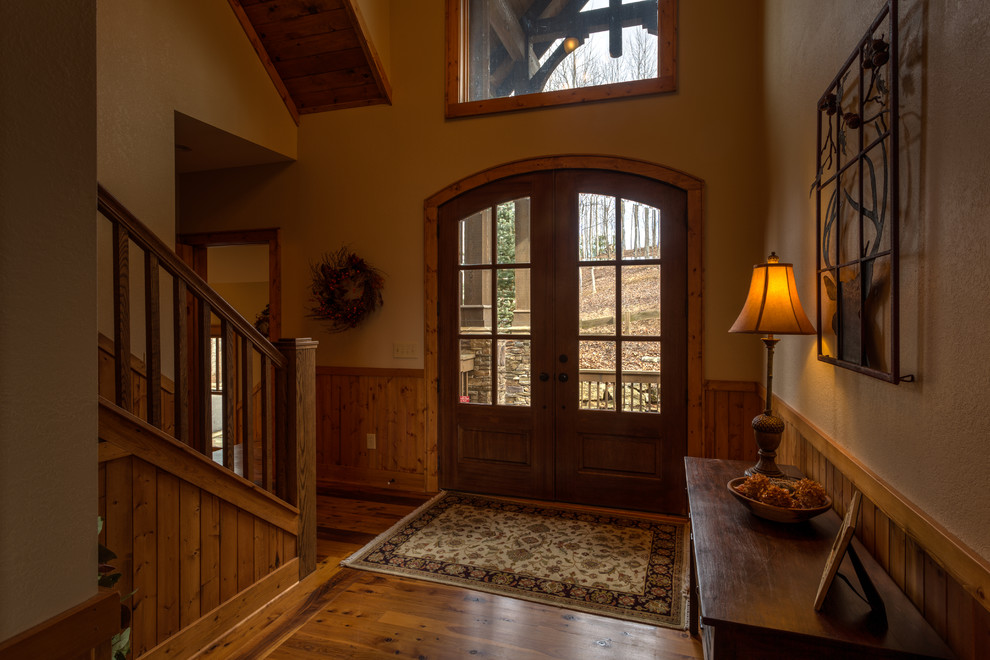 Inspiration for a large country foyer in Charlotte with yellow walls, medium hardwood floors, a double front door and a medium wood front door.
