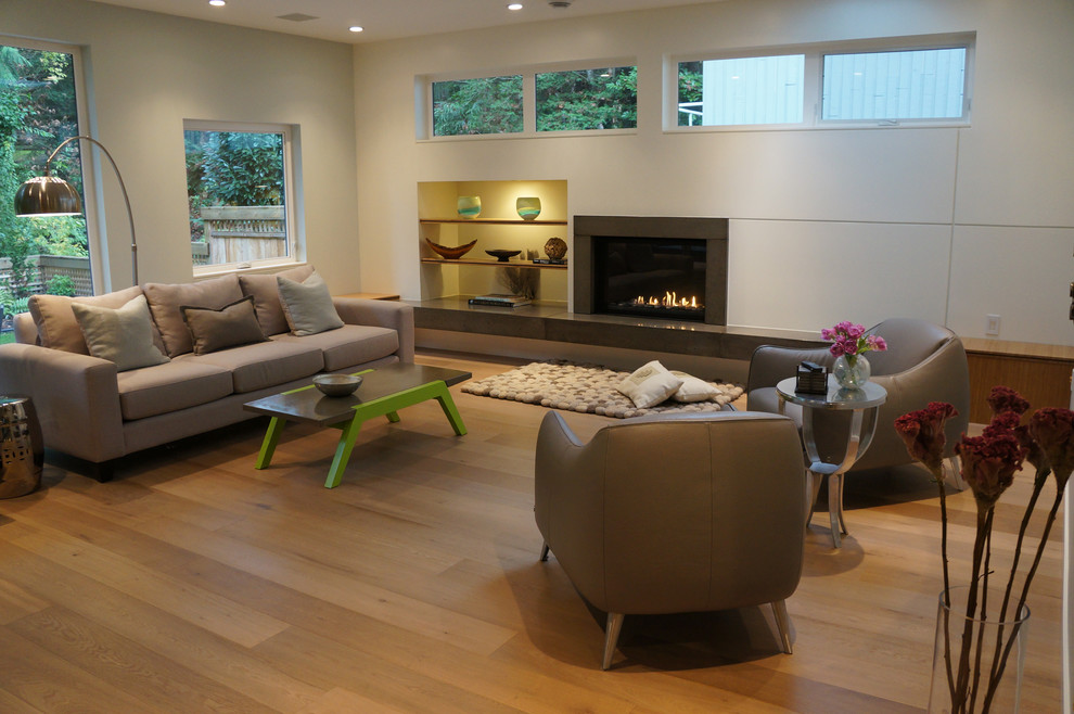 This is an example of a mid-sized contemporary enclosed family room in Vancouver with white walls, light hardwood floors, a standard fireplace, a concrete fireplace surround and no tv.