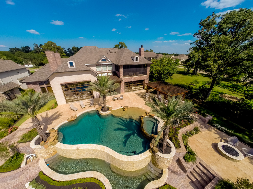 This is an example of a large traditional backyard custom-shaped natural pool in Houston with a hot tub and concrete slab.