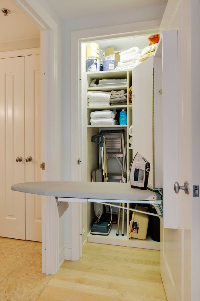 Photo of a small contemporary single-wall utility room in Boston with open cabinets, white cabinets, white walls and light hardwood floors.