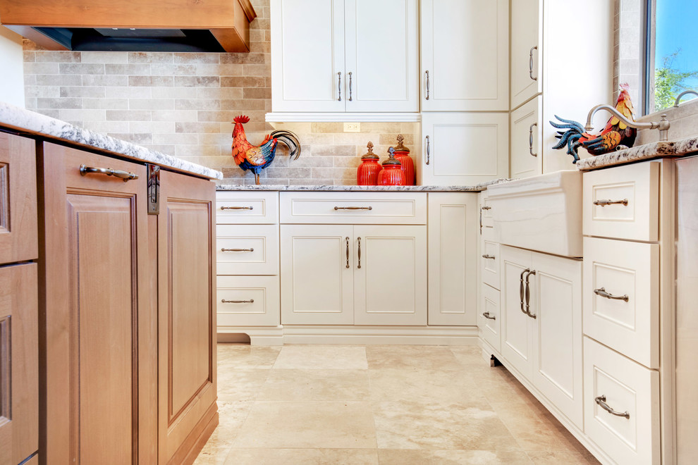 Open concept kitchen - large transitional u-shaped travertine floor and beige floor open concept kitchen idea in Phoenix with a farmhouse sink, recessed-panel cabinets, white cabinets, granite countertops, gray backsplash, porcelain backsplash, stainless steel appliances, an island and multicolored countertops