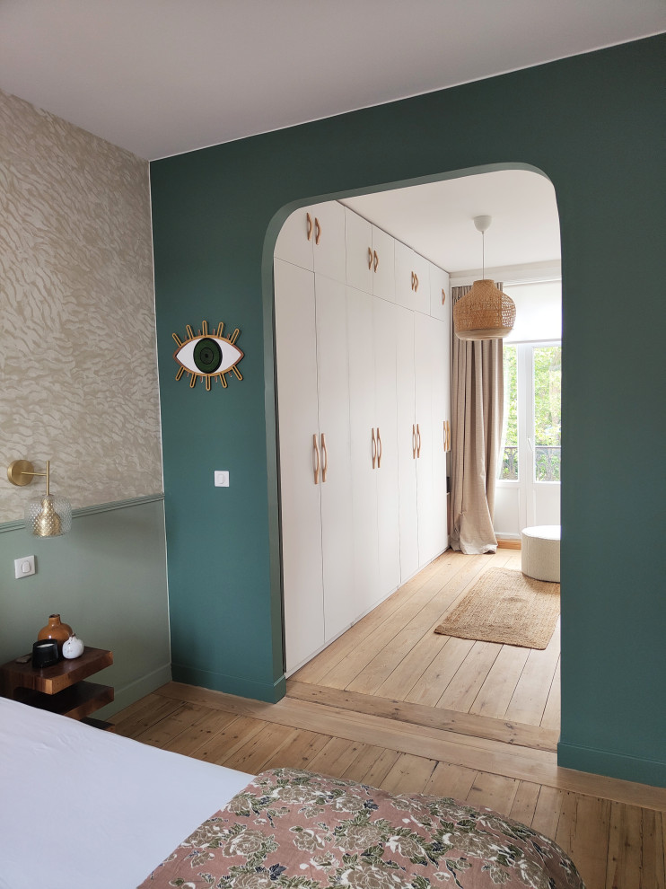 This is an example of a mid-sized transitional master bedroom in Lille with green walls, light hardwood floors and no fireplace.
