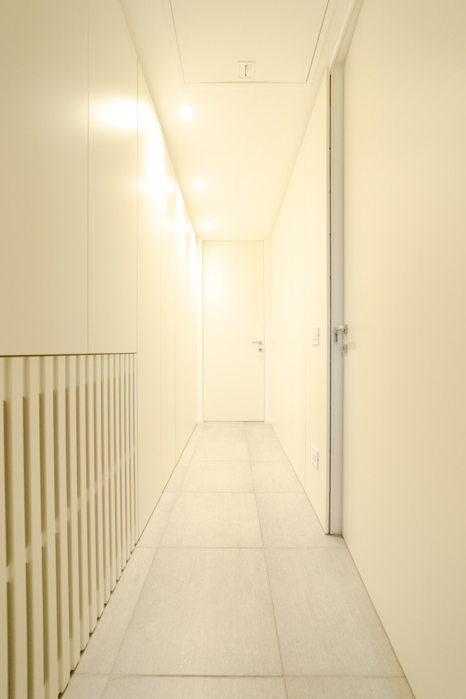 Modern inredning av en mellanstor hall, med vita väggar, klinkergolv i porslin och grått golv