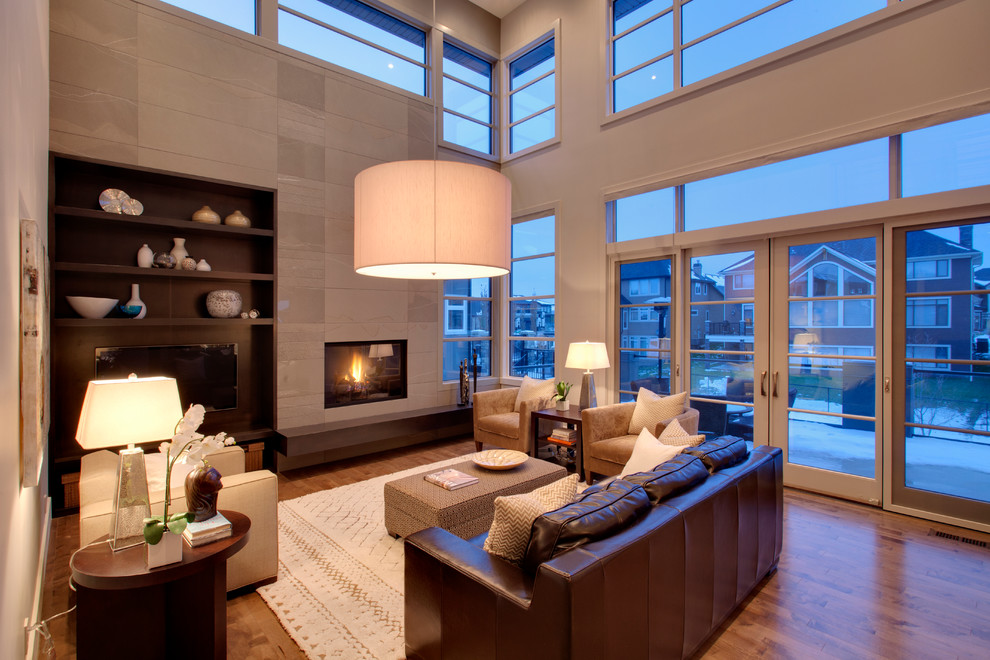 Inspiration for a contemporary living room in Calgary with grey walls, medium hardwood floors, a tile fireplace surround and a wall-mounted tv.