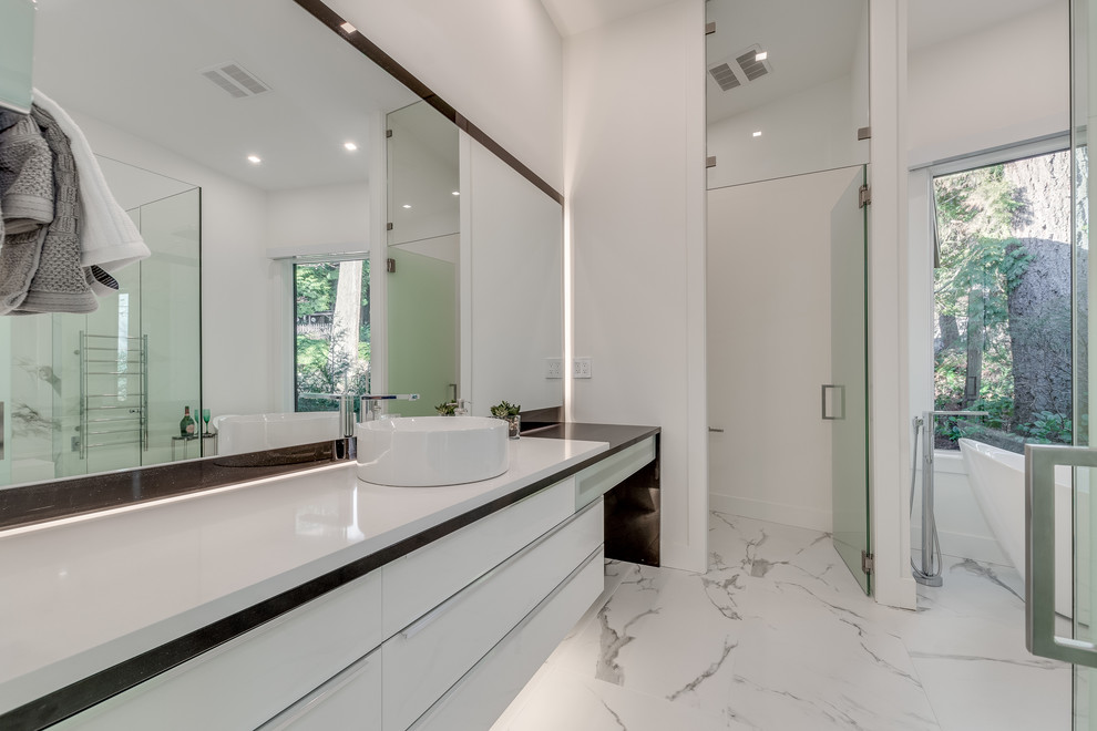 Photo of a mid-sized modern master bathroom in Vancouver with glass-front cabinets, white cabinets, a freestanding tub, an open shower, white tile, stone tile, white walls, marble floors, a vessel sink, engineered quartz benchtops, white floor, a hinged shower door, white benchtops and a wall-mount toilet.