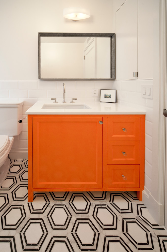 Photo of a small transitional 3/4 bathroom in New York with recessed-panel cabinets, orange cabinets, an alcove tub, an alcove shower, a two-piece toilet, white tile, ceramic tile, white walls, marble floors, an undermount sink, quartzite benchtops, grey floor and a shower curtain.