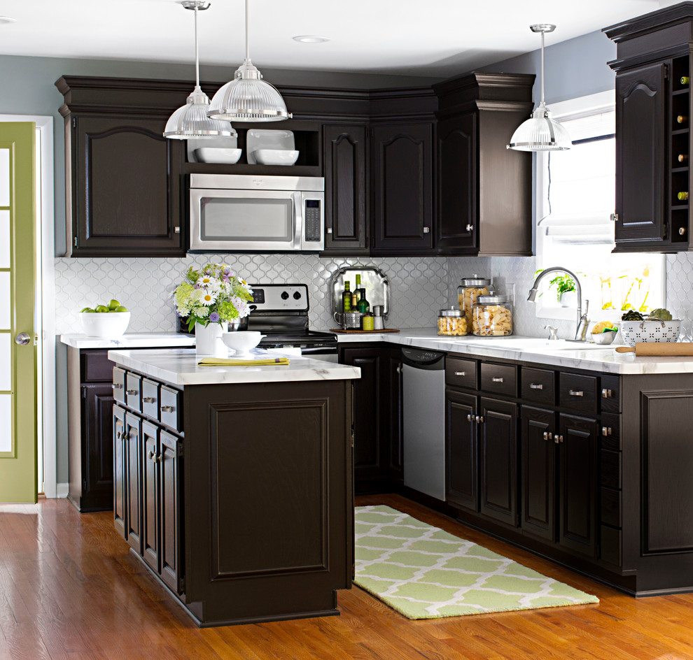 Enclosed kitchen - large transitional l-shaped medium tone wood floor enclosed kitchen idea in Charlotte with a double-bowl sink, raised-panel cabinets, dark wood cabinets, white backsplash, stainless steel appliances and an island