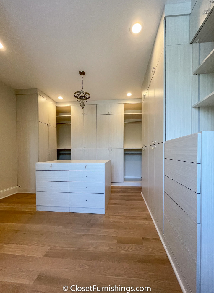 This is an example of a large modern gender neutral walk-in wardrobe in Chicago with flat-panel cabinets and light wood cabinets.