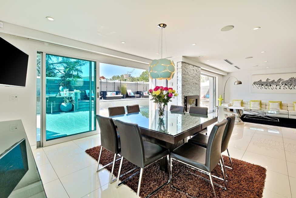 Photo of a large contemporary open plan dining in Los Angeles with white walls, porcelain floors, a standard fireplace, a stone fireplace surround and white floor.