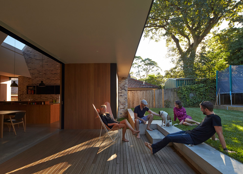 This is an example of a mid-sized contemporary backyard deck in Sydney with a roof extension.