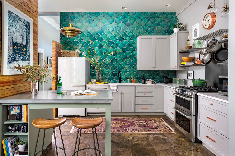 Design ideas for an eclectic l-shaped kitchen in Atlanta with an undermount sink, shaker cabinets, grey cabinets, quartz benchtops, green splashback, ceramic splashback, stainless steel appliances, concrete floors, brown floor, white benchtop and a peninsula.