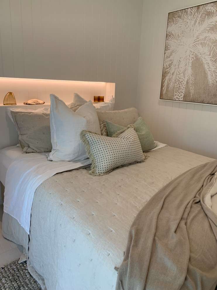 Example of a small beach style master porcelain tile, white floor and shiplap wall bedroom design in Sunshine Coast with white walls