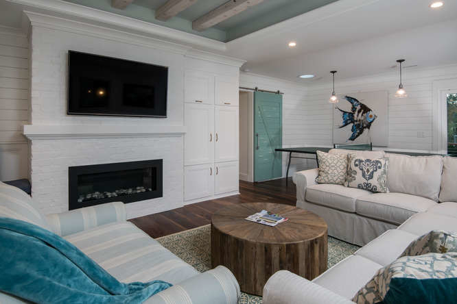Photo of a beach style enclosed living room in Charleston with white walls, dark hardwood floors, a ribbon fireplace, a brick fireplace surround, a wall-mounted tv and brown floor.
