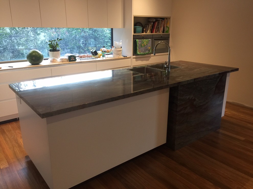 Inspiration for a mid-sized modern kitchen in Sydney with granite benchtops, stone slab splashback and light hardwood floors.