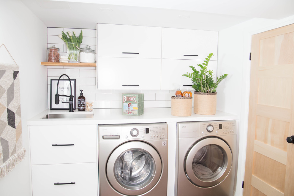 Inspiration for a small modern dedicated laundry room in Toronto with an undermount sink, flat-panel cabinets, white cabinets, quartz benchtops, white walls, ceramic floors, a side-by-side washer and dryer and black floor.
