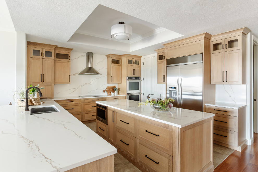 Large transitional u-shaped ceramic tile, beige floor and tray ceiling open concept kitchen photo in Tampa with an undermount sink, shaker cabinets, light wood cabinets, quartz countertops, white backsplash, quartz backsplash, stainless steel appliances, an island and white countertops